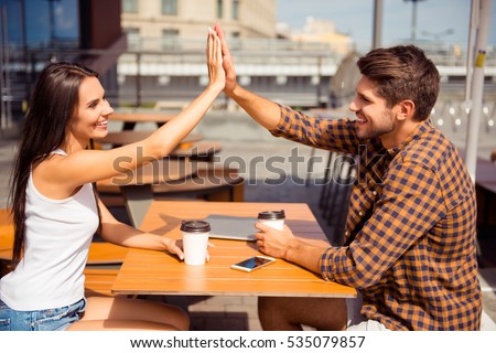 Happy pretty woman giving high five to her boyfriend in cafe Royalty-Free Stock Photo #535079857