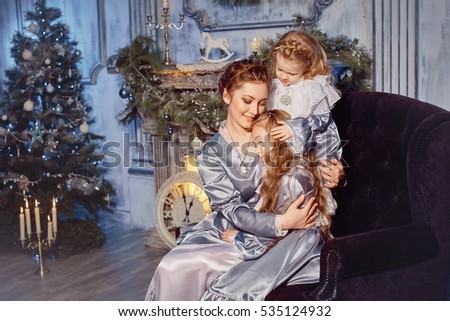 Cute little  girls and his mother. Vintage style. Christmas background Christmas tree and a fireplace. Girl hugging her mother gently. The concept of motherhood