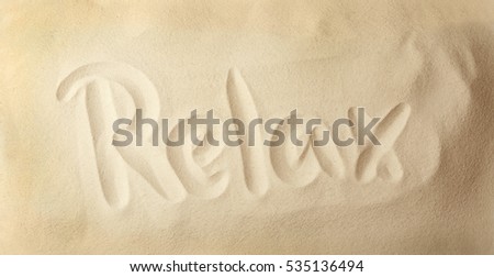 Word RELAX written on sand