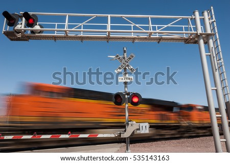 Zooming train engine speeding past railroad crossing Royalty-Free Stock Photo #535143163