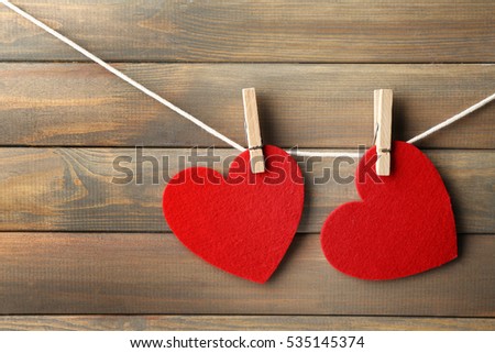 Red hearts hanging on clothespins on wooden background