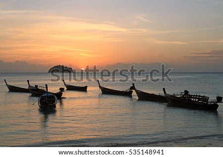 Peaceful and beautiful scene of local wooden boats with dawn sky and sun light at Sunrise beach at Lipe Island, Thailand. Using as nature, seascape, landscape, lifestyle, transportation background