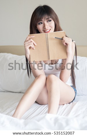 Portrait of a young woman sitting at home with pencil and paper, beautiful girl thinks.