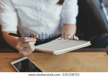 Woman writing in the notebook and drinking coffee,Toned picture.
