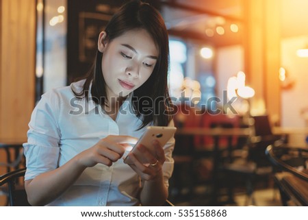 Young woman using smartphone with a coffee cup and notebook.Toned picture.