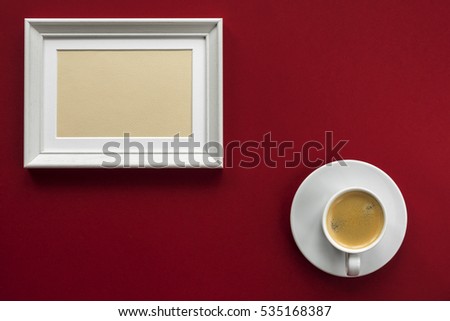 little white wooden frame on red vinous background with little white cup of aromatic black espresso