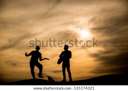 Silhouette A man playing the guitar Another man dancing