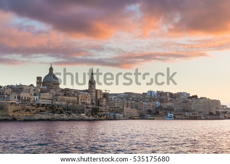 Beautiful Valletta skyline under a vibrant colorful golden sunset, seen across the water from the paths around Tigne Point, Sliema, Valletta is the capital city of Malta, Europe