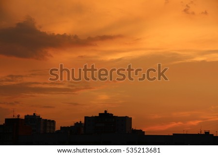Silhouettes of city buildings on a bright dramatic sunset background 