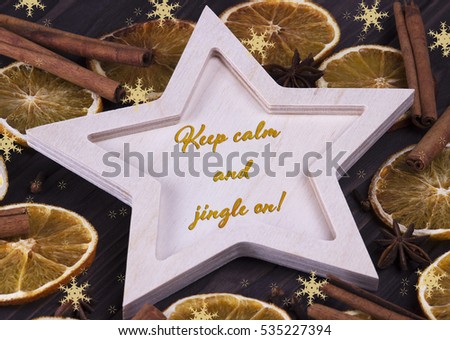 Christmas Xmas New Year Holiday greeting card with wooden star cinnamone star anice dried oranges snowflakes and text Keep calm and jingle on