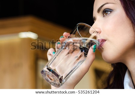 Face of the girl or woman close up drinking water from large glasses in a restaurant or cafe