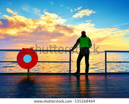 Alone man on pier and look over handrail into water. Sunny sky, smooth water level. Vivid and strong vignetting effect