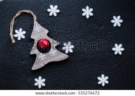 Little white Christmas snowflakes decoration and wooden Christmas toy on black textured background. Winter wallpaper. Flat lay, top view.