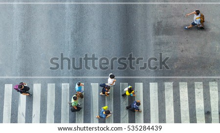 the one man walk converse,  the busy city crowd move to pedestrian crosswalk on businees traffric road (Aerial photo, top view)  Royalty-Free Stock Photo #535284439