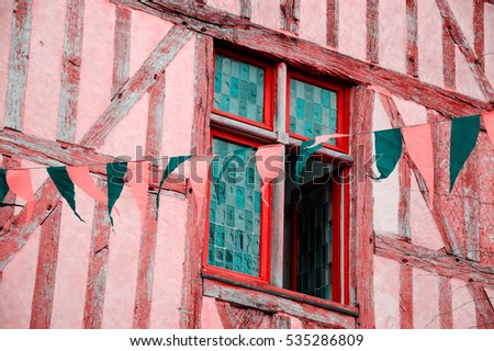  Half-timbered house and festive flags garland. France. Toned photo.