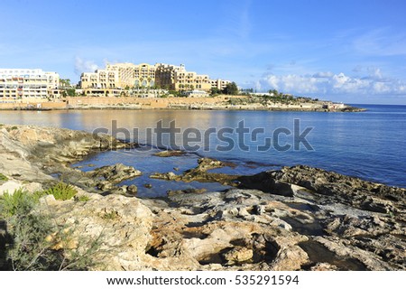 rocky seashore with buildings on the other side of bay, Malta, Europe
