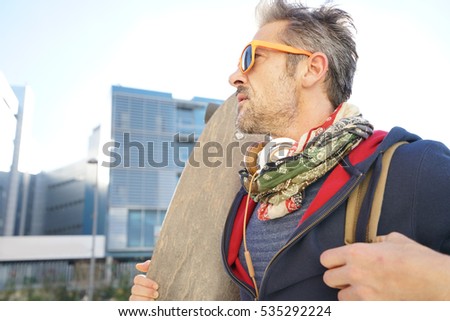 Skateboarder in town holding skateboard on shoulder