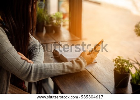 A female reading the bible play a cell phone in the cafe. Royalty-Free Stock Photo #535304617