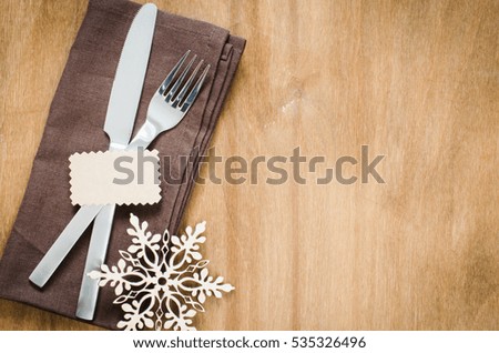 Winter Table Setting. Silverware with Empty Tag and Linen Napkin on Rustic Wooden Background. Top View. Copy Space. Selective Focus.