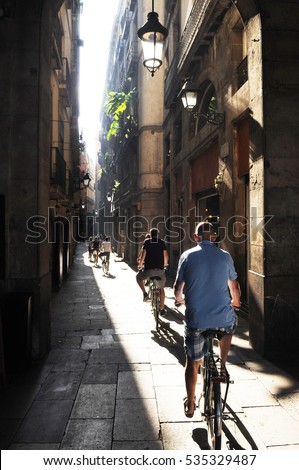 group of cyclists on a narrow street Barcelona Royalty-Free Stock Photo #535329487