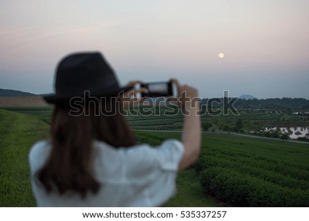 Women who travel a phone photography tea plantation.