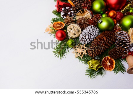 Christmas decoration with pine cones, red balls and green ornaments. Christmas greeting background with baubles and dried orange slices. Copy space.