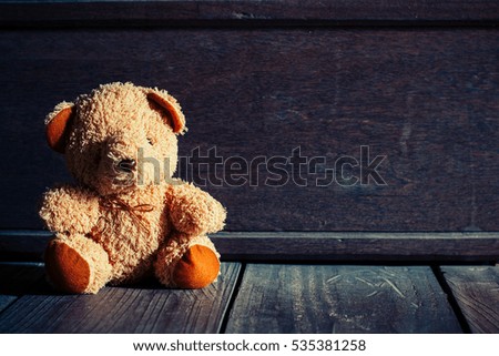 Cute teddy bear sitting on old wood background