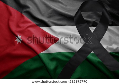 waving national flag of jordan with black mourning ribbon