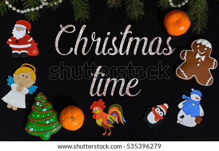 Xmas composition with text Christmas time on school blackboard and the Christmas decorations, toys (Santa Claus, Angel, a rooster, a snowman, a penguin) and tangerine