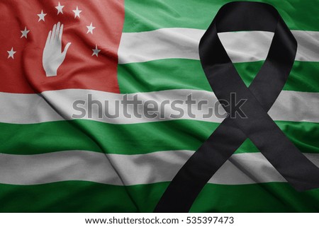 waving national flag of abkhazia with black mourning ribbon