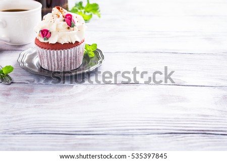 Dessert for Valentines Day, beautiful red velvet cupcake decorated with pink rose on old white wooden background with copy space.