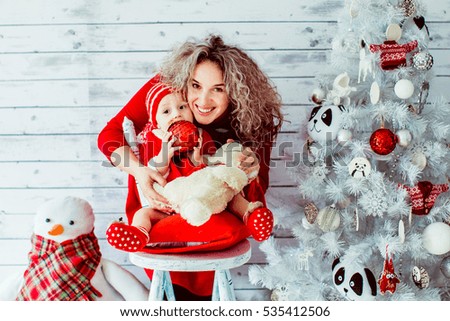 The mother with daughter sitting near Christmas tree