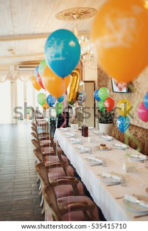 Colorful balloons hang over long dinner table