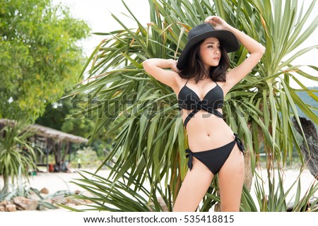 Happy woman enjoying beach relaxing joyful in summer by tropical blue water. Beautiful bikini model happy on travel wearing bikini.