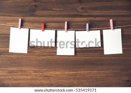 rows of empty photo frames hanging with clothespins on wooden background 