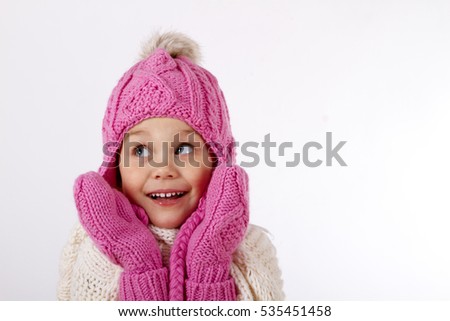 Pretty charming little girl in a knitted hat and a mittens. He is smiling and looking up. close-up portrait