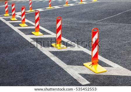 Traffic safety. Traffic markings on a gray asphalt. Red and white striped caution road sign