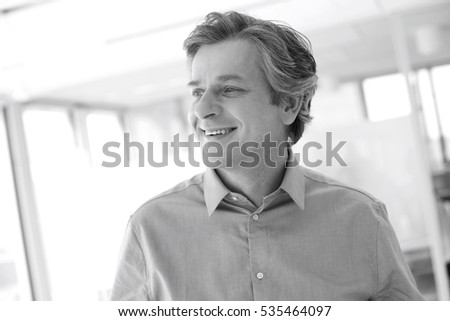 Smiling mature businessman looking away at office Royalty-Free Stock Photo #535464097