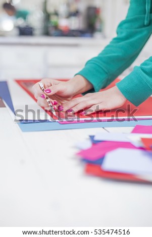 Young woman make scrapbook of the papers on the table using antique tools for cutting paper. Hand made photo album.Shallow depth of field