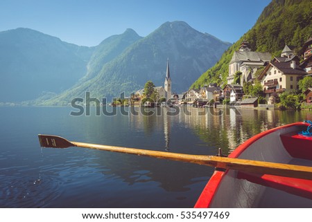 Scenic picture-postcard view of famous Hallstatt lakeside village in the Austrian Alps with traditional rowing boat in beautiful morning light on a sunny day in summer, Salzkammergut region, Austria