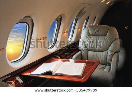 luxury interior in the modern  business jet and sunlight at the window/sky and clouds through the porthole Royalty-Free Stock Photo #535499989