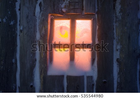 After the storm a strong frost frosted alpine peaks of the Carpathians in Ukraine, and the bright colors of Christmas huts on wild forests of spruce and pine glowing hut window with tourists
