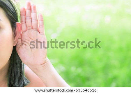 Asian woman hold her hand near her ear and listening in green field Royalty-Free Stock Photo #535546516