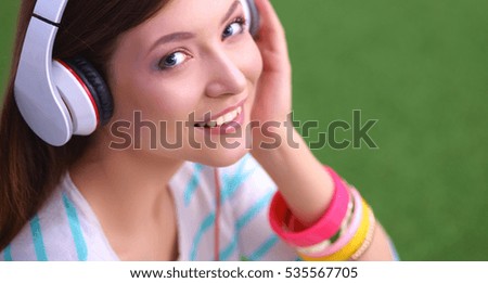 Woman listening to the music sitting on green grass