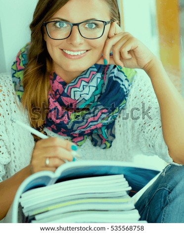 Happy student girl sitting with pile of books