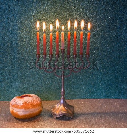 Jewish menorah with glitter burning candles and sweet donuts are traditional symbols for Hanukkah holiday
