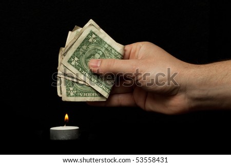 Male hand burning dollars, isolated on black background