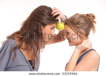 Two girls holding an apple with their foreheads