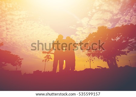 Silhouette of two men hug on sunset.