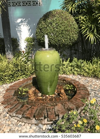 Green jar fountain in garden on background